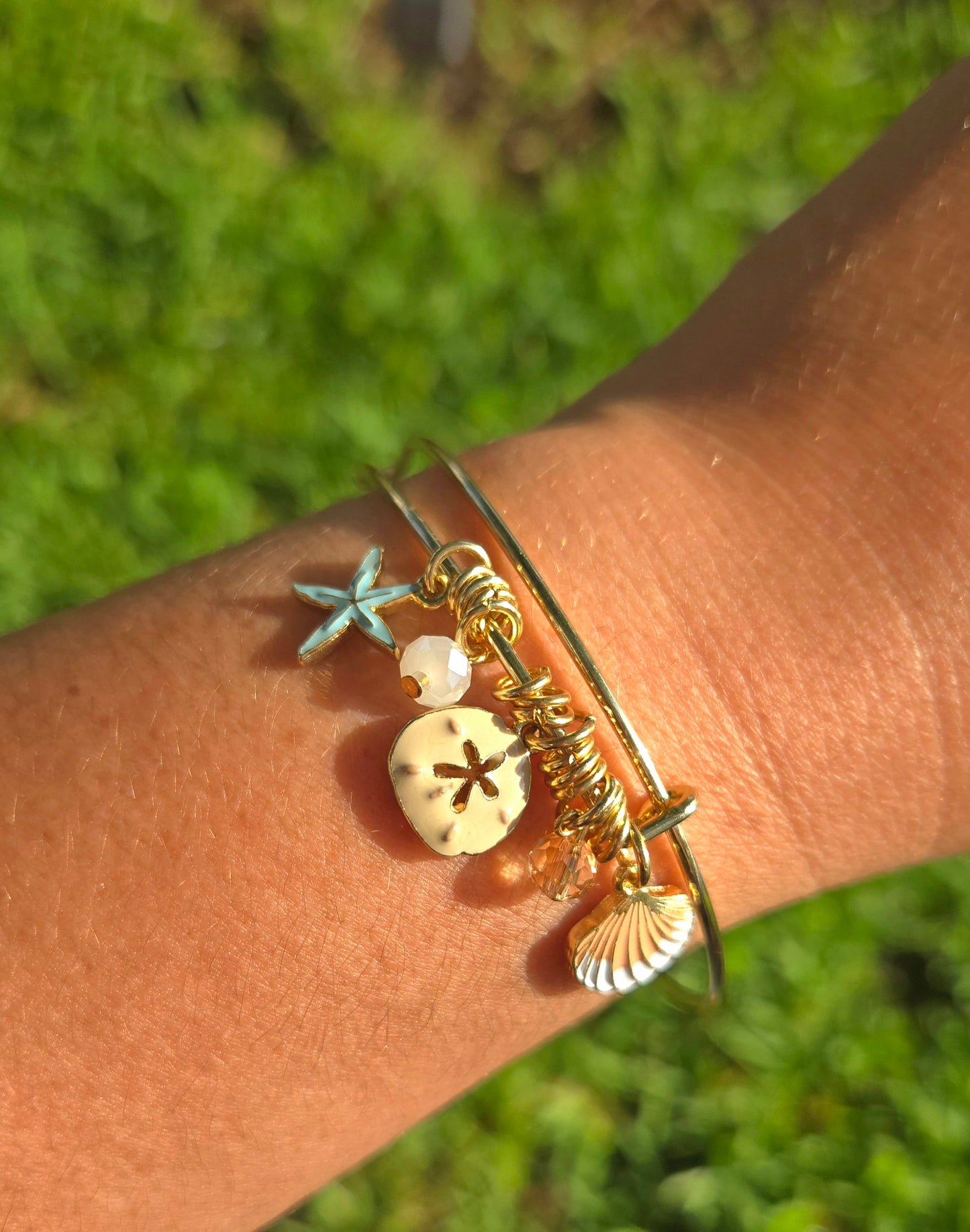 Pulsera bangle dorada decorada con concha, estrella de mar y cristales
