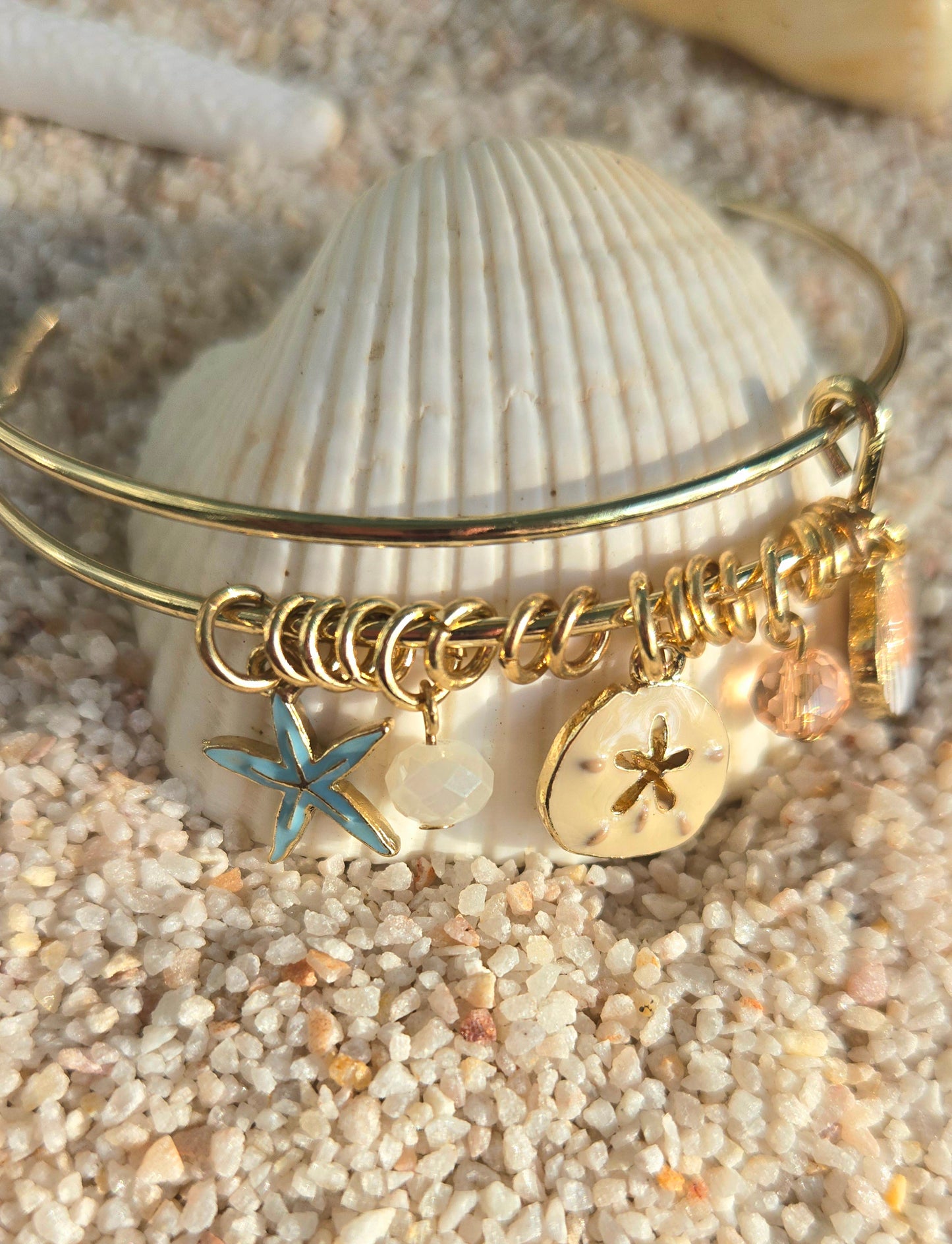 Pulsera bangle dorada decorada con concha, estrella de mar y cristales