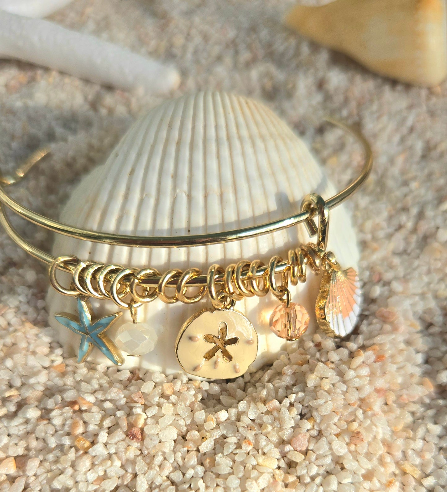 Pulsera bangle dorada decorada con concha, estrella de mar y cristales